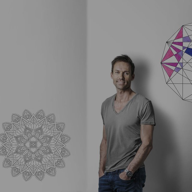 Sven Hannawald lehnt an einer Wand auf der halb ausgemalte Mandalas zu sehen sind 