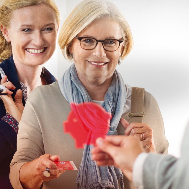 Zwei Kundinnen der Sparkasse Fürth erhalten ein kleines rotes Schweinchen.
