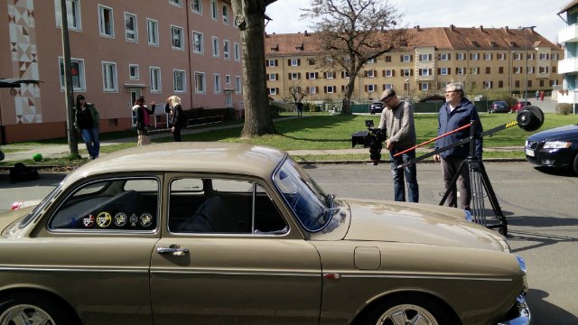 Ein altes Auto wird von einem Mann mit Kamera gefilmt.