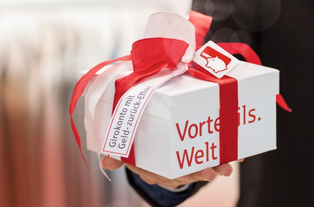 Ein weißes Geschenk mit rotem Geschenkbank umwickelt auf dem Vorteils.Welt steht