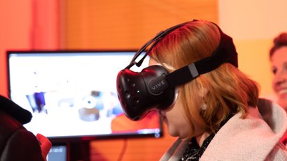 Besucherin auf der Langen Nacht der Wissenschaft am Ergo Stand mit einer VR-Brille auf dem Kopf.