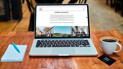 Schreibtisch mit Laptop und Webseite Neue Höfe, sowie Visitenkarte am Tisch