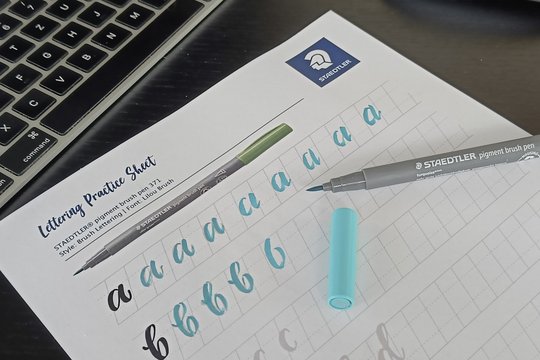 Lettering Übungen vom Hand Lettering Creator werden mit einem Stift auf Papier gemacht.