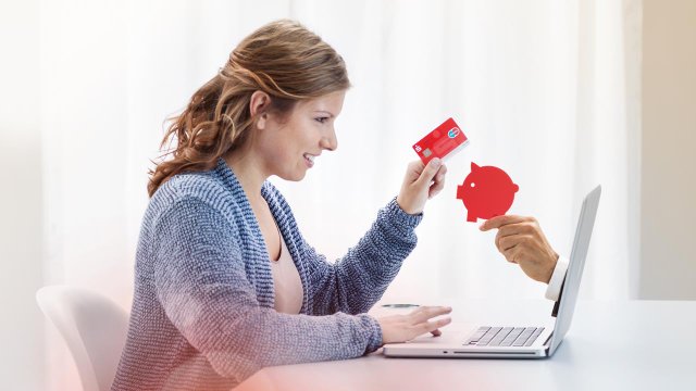 Aus dem Laptop der Sparkassen-Kundin reicht eine Hand der Kundin ein Sparschwein entgegen