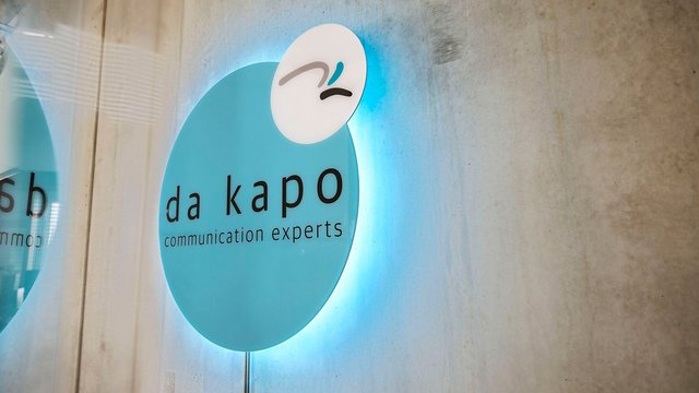 beleuchtetes da kapo Logo an einer Betonwand