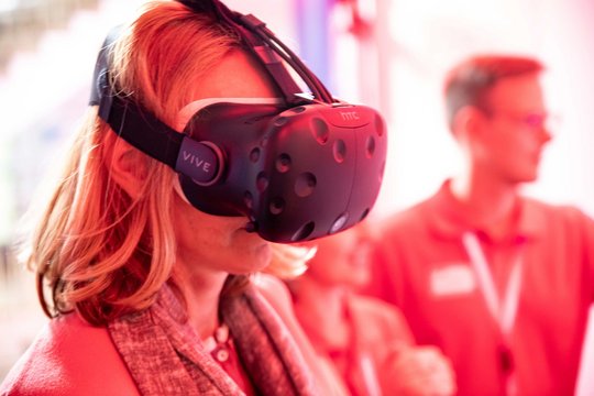 Besuchende auf der Langen Nacht der Wissenschaft am Ergo Stand mit einer VR-Brille.