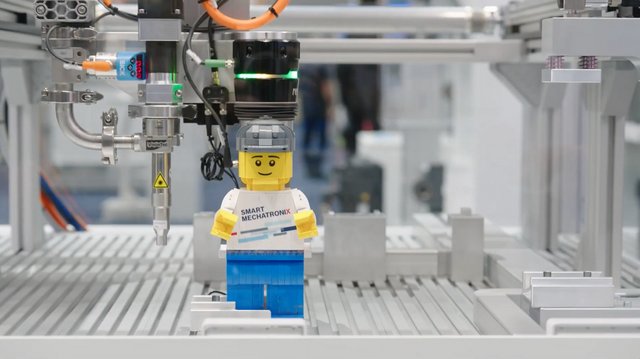 Ein Legomännchen steht in einem Lineartechnik-Roboter auf dem Bosch Rexroth Messestand