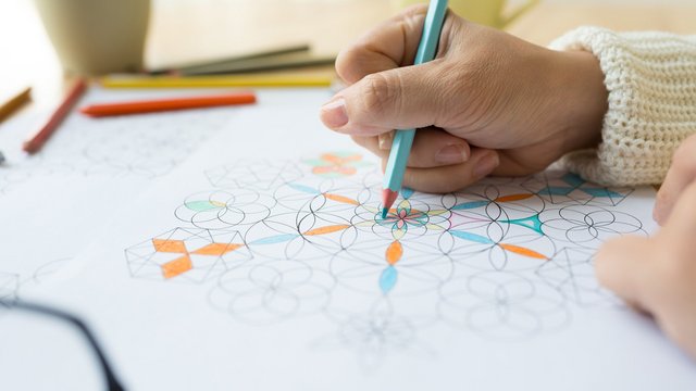 Ein Mandala wird mit Buntstiften ausgemalt.