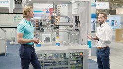 Ein Mitarbeitender von Bosch Rexroth erklärt einem Besuchenden der Messe das Smart Funktion Kit.