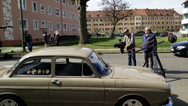 Ein altes Auto wird von einem Mann mit Kamera gefilmt.