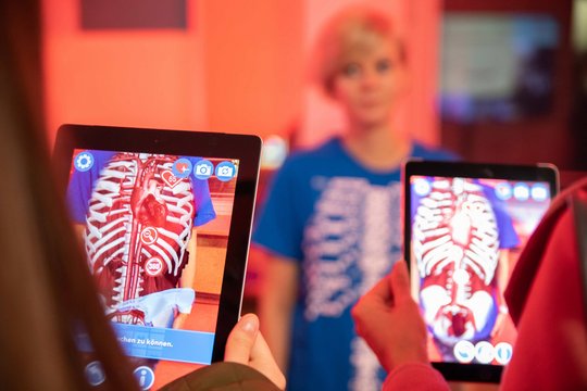 Besuchende auf der Langen Nacht der Wissenschaft am Ergo Stand mit Tablets in der Hand.