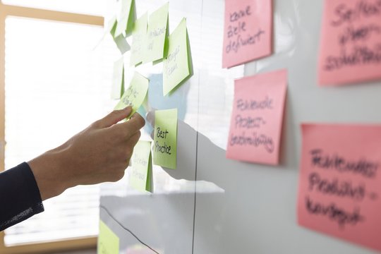 Teammitglieder von da kapo Communication Experts hängen bunte Post-its an eine Wand.